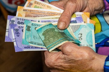 India money. Indian senior woman holding Indian rupees in her hands. Financial and economic concept. Financial situation of senior citizens in India
