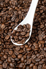 Freshly roasted coffee decaffeinated beans in a spoon close-up