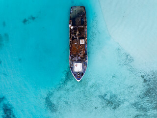 Aerial view of a half sunken ship at Maldives, Indian ocean. Big rusty ship is on this photo in a...