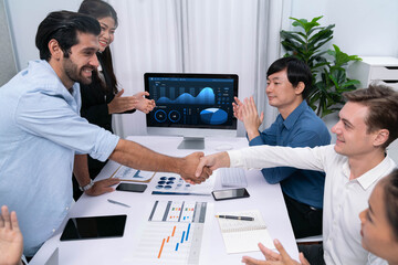 Analyst team leader shake hand with his colleague after successful data analysis meeting using FIntech software power with business intelligence or BI dashboard. Prudent