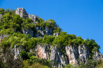 Stunning rocky cliffs adorned with lush green vegetation under a bright blue sky in a remote natural landscape