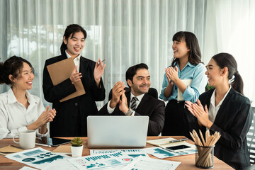 Group of happy businesspeople in celebratory gesture and successful efficient teamwork. Diverse race office worker celebrate after made progress on marketing planning in corporate office. Habiliment
