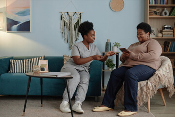 Full length of smiling African American elderly woman learning how to pay bills online using...
