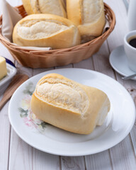 French bread or salt bread with butter and coffee over white wooden table