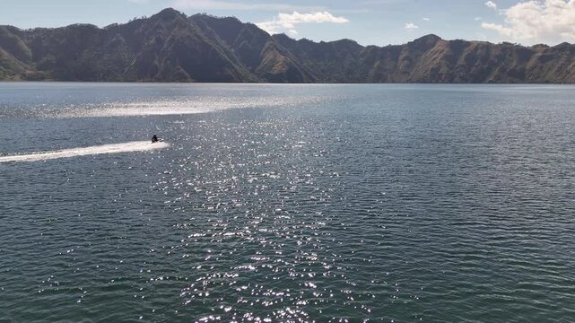 Vista panor&aacute;mica de lago profundo entre monta&ntilde;as con lancha r&aacute;pida dejando estela