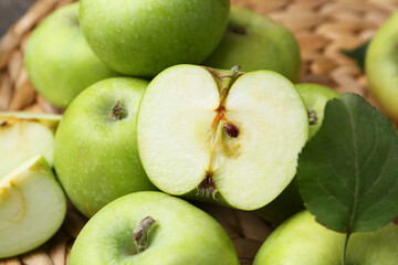 Whole and cut green apples on wicker mat, closeup