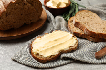 Fresh bread with butter on grey table, closeup