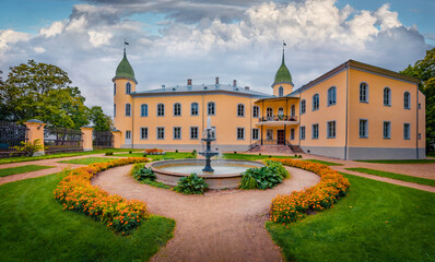 Fototapeta premium Beautiful summer view of Krustpils Castle with flower bed and fountain. splendid morning cityscape Jekabpils town, Latvia, Europe. Traveling concept background.