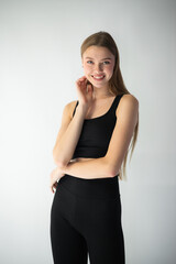 professional model in a sleek black outfit adjusts her jeans while gazing off-camera, showcasing...