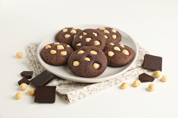 Tasty chocolate cookies with hazelnuts on white table, closeup