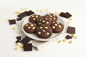 Tasty chocolate cookies with hazelnuts on white table