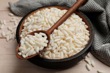 Puffed rice in bowl and spoon on white wooden table, closeup