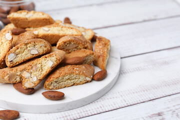 Tasty almond biscuits (Cantuccini) and nuts on light wooden table, closeup. Space for text