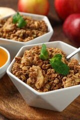 Tasty apple crisp in bowls, fresh fruits, honey and spoon on table, closeup