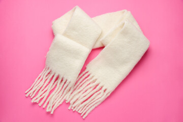 Warm woolen scarf on pink background, top view