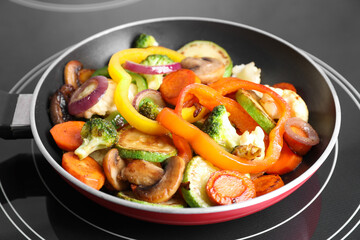 Frying pan with mix of vegetables and mushrooms on cooktop, closeup