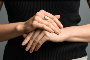 Woman wearing beautiful golden ring on grey background, closeup