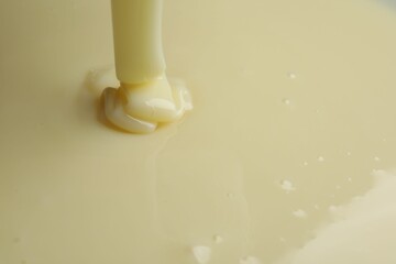 Pouring delicious condensed milk as background, closeup