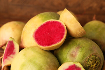 Whole and cut fresh turnips on blurred background, closeup