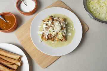 Golden tacos with cabbage, cheese, and cream preparing on a white plate