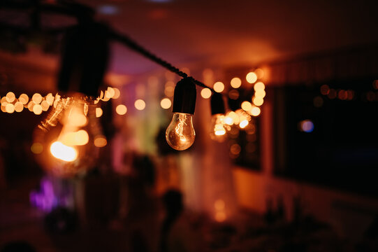 A romantic wedding party scene illuminated by string lights, creating a warm and cozy atmosphere for the celebration.
