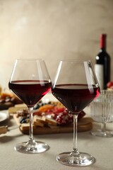 Red wine and different snacks served on light grey table