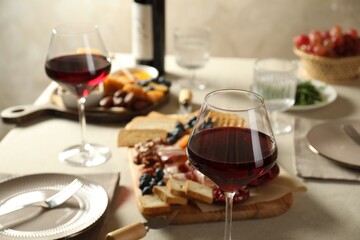 Red wine and different snacks served on table, closeup