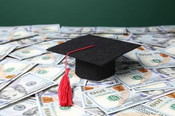 Graduate hat on dollar banknotes, closeup. Tuition payment