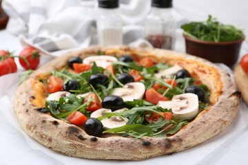 Tasty pizza with cherry tomatoes, black olives, mushrooms and arugula on white tiled table, closeup