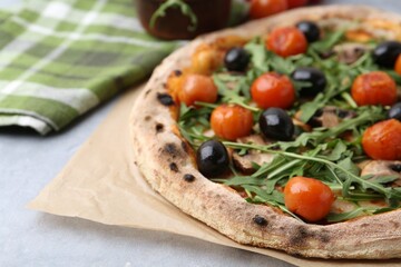 Tasty pizza with cherry tomatoes, black olives, mushrooms and arugula on grey table, closeup. Space for text
