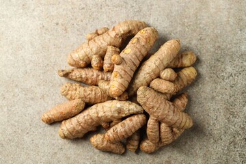 Pile of tumeric rhizomes on grey table, top view