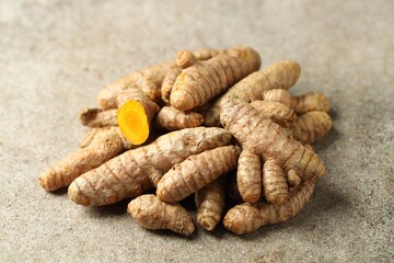 Pile of tumeric rhizomes on grey table, closeup