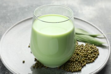 Fresh mung bean juice in glass, seeds and green leaves on table, closeup