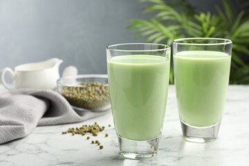 Fresh mung bean juice in glasses and seeds on white marble table