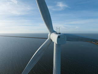 Wind turbine on water, close up view, renewable energy. Aerial drone view.
