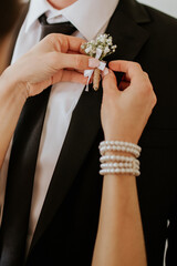 Bride Attaching Boutonniere to Groom’s Suit