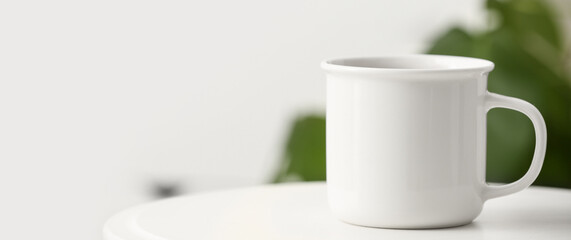 White mug on table in room. Banner for design