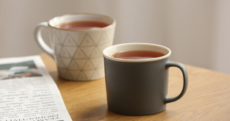 Mugs of black hot tea on wooden table in room