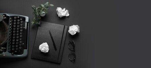 Vintage typewriter, notebook, eyeglasses and crumpled paper on black background with space for...