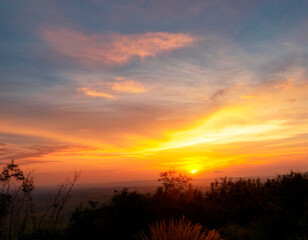 Fototapeta premium Atardecer sobre la montaña, con cielo naranja, amarillo y azul