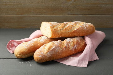 Cut fresh baguettes on grey wooden table