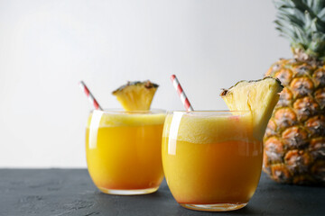 Tasty pineapple cocktail in glasses served on black table