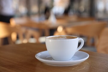Cup of aromatic coffee on wooden table in cafe, closeup. Space for text