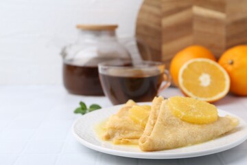 Delicious Crepes Suzette served on white tiled table, closeup