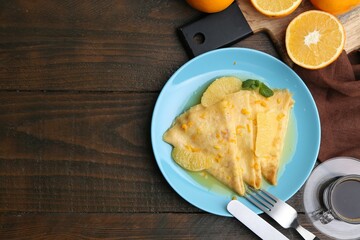 Tasty crepes Suzette served on wooden table, flat lay. Space for text