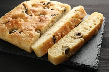 Pieces of delicious focaccia bread with olives and thyme on dark wooden table, closeup