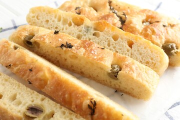 Slices of delicious focaccia bread with olives, thyme and salt on table, closeup