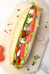 Delicious baguette with salmon on white marble table, top view