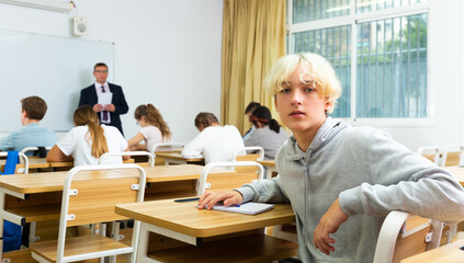 Obraz premium Portrait of teenager who is posing at the desk in the class