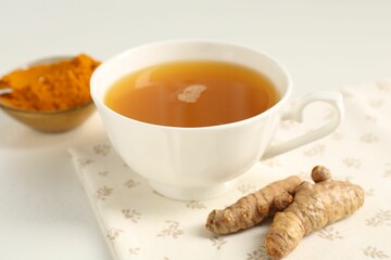 Aromatic turmeric tea, powder and rhizomes on white table, closeup